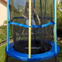 Fetiță sărind pe trambulină cu plasă de protecție
